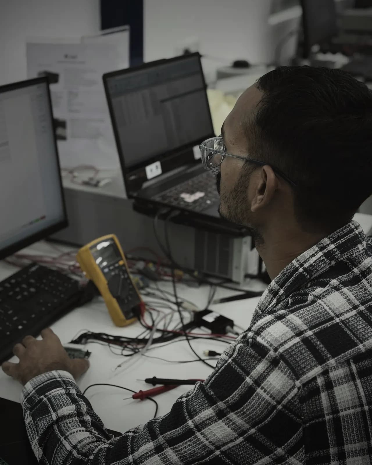 Engineer validating a battery-management board with a multimeter