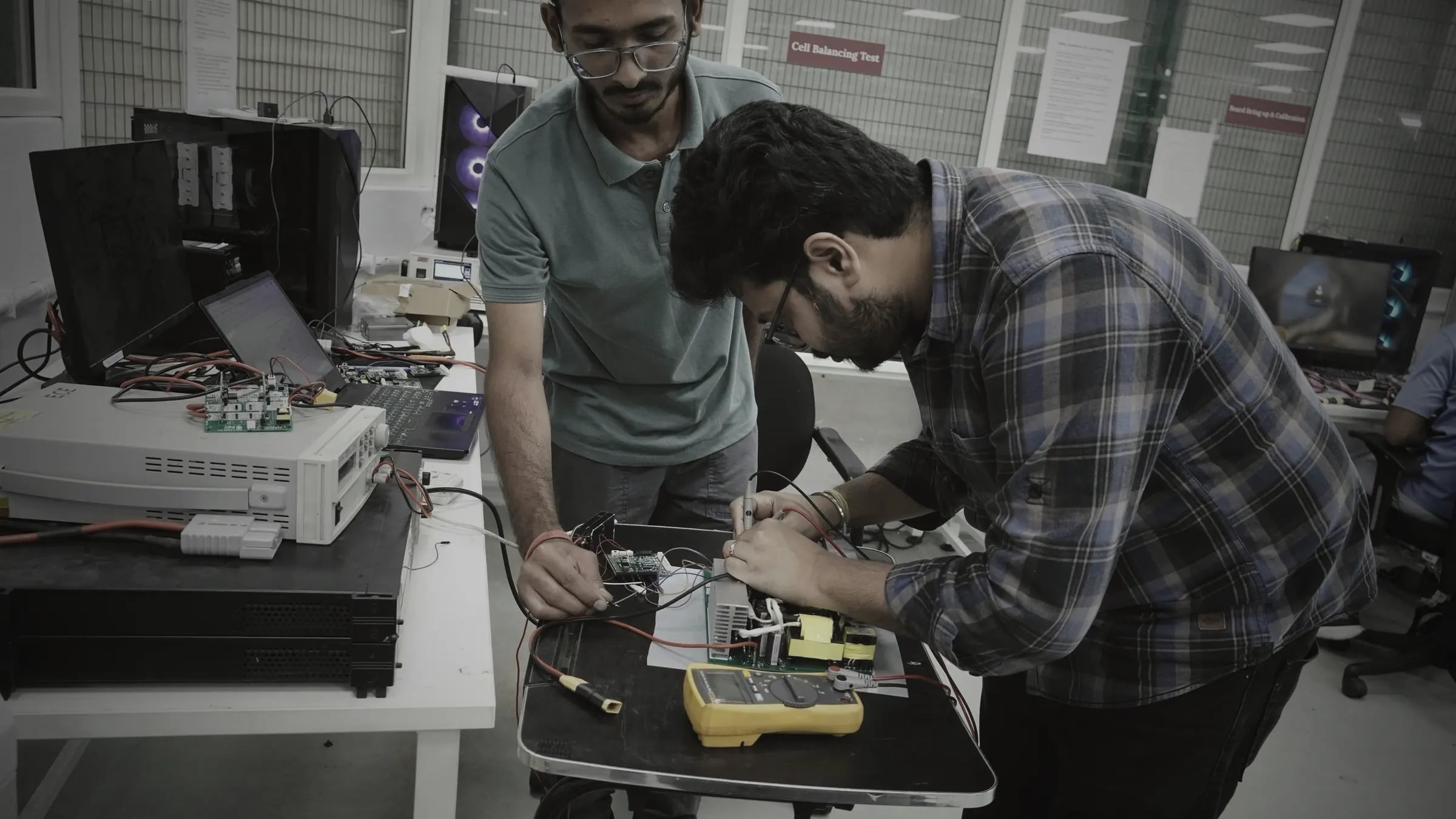 Engineers bringing up and calibrating a charger power board on the in-house test bench